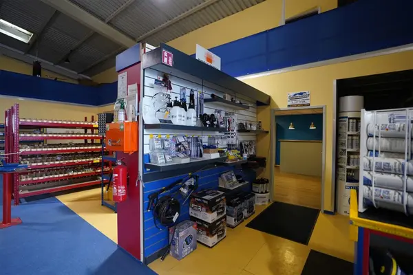 Regal mit Werkstattbedarf, Werkzeugen und Ersatzteilen in einem gut beleuchteten Fachgeschäft.