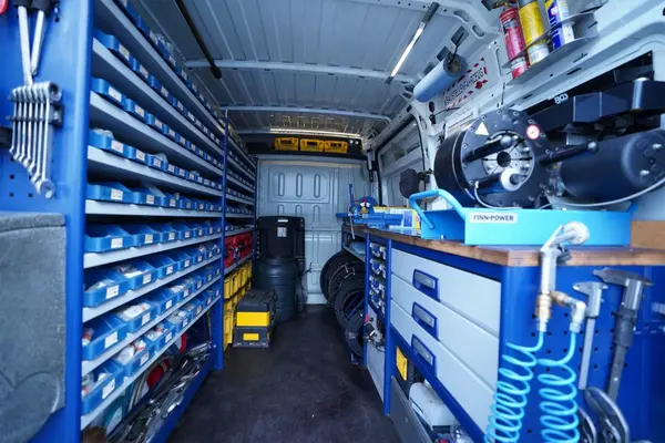 Werkstattwagen-Innenraum mit Regalen, Werkzeugen und Maschinen für mobile Reparaturen.