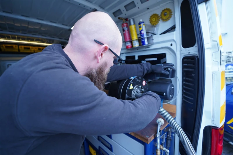 Ein Monteur arbeitet im Servicefahrzeug an einer Hydraulik-Schlauchpresse.